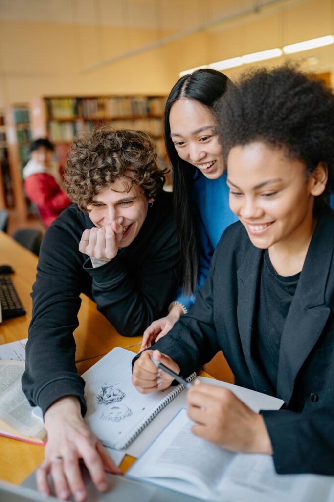 Group of smiling teenagers studying together in a library environment.