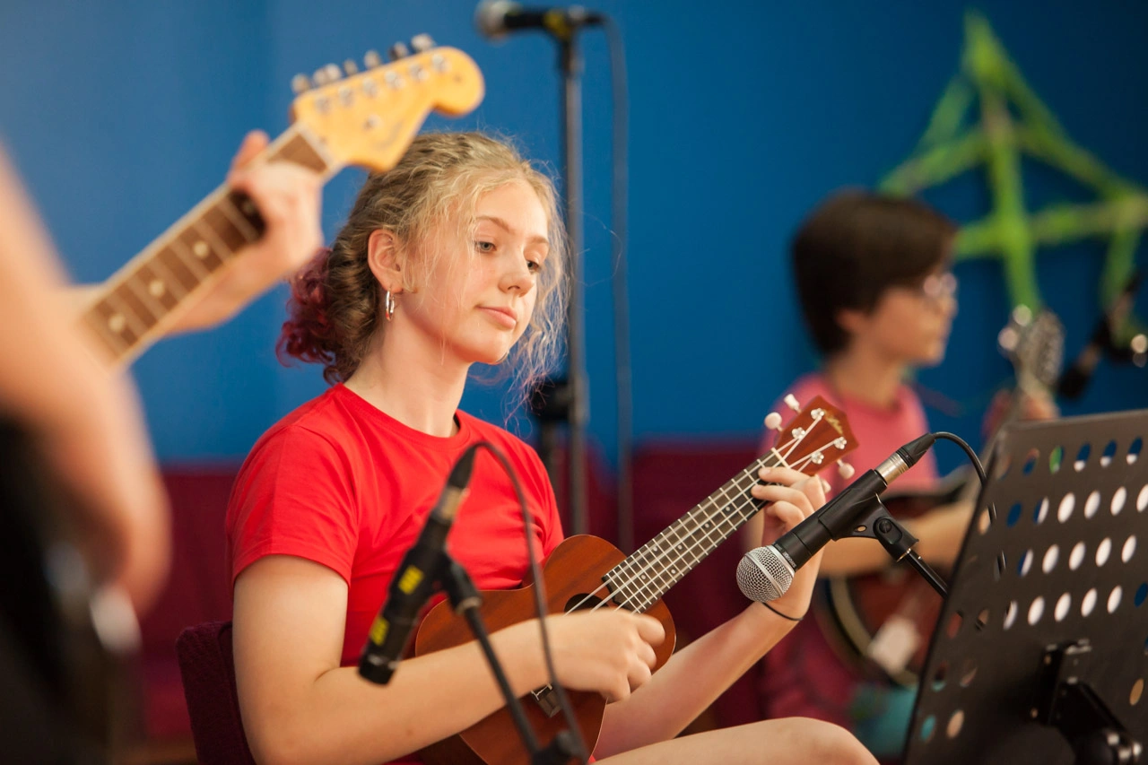 Student playing the ukulele during a music performance at BISC British International School of Cracow